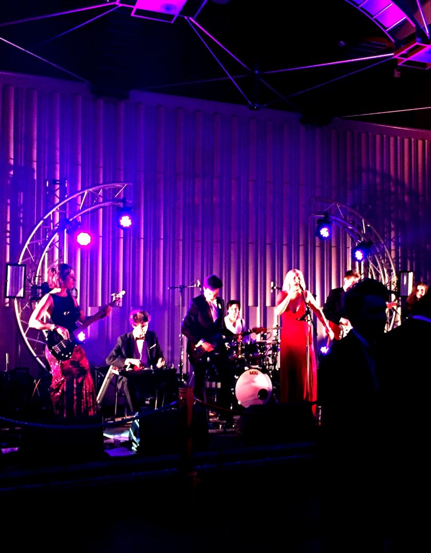 A band, shrouded in purple light perform in the Wolfson Hall at the Teddy Hall Ball