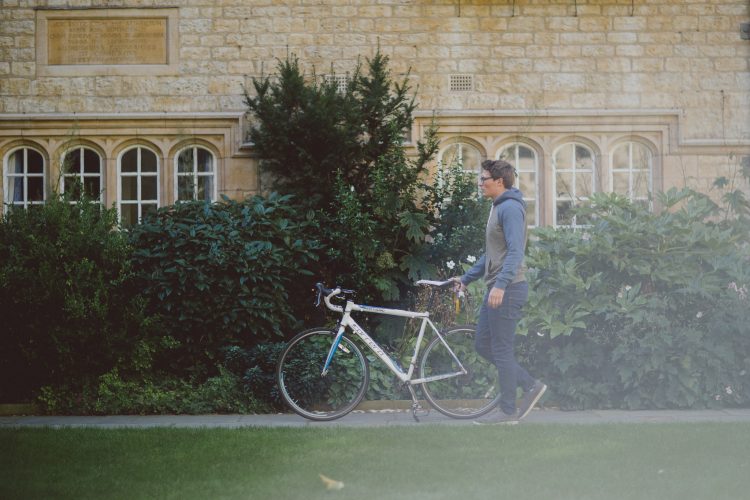 Fresher student pushing their bike through the front quad on moving in day