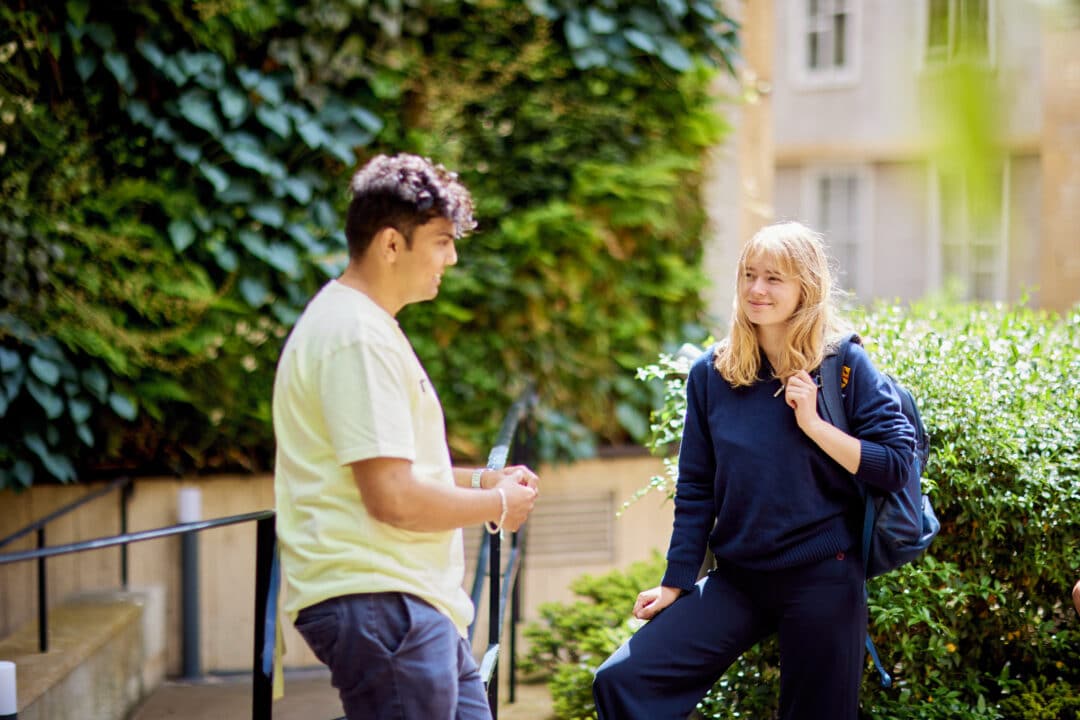 A group of St Edmund Hall students chatting in front of the living wall