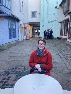 Alex sat at a table wearing a red jumper.