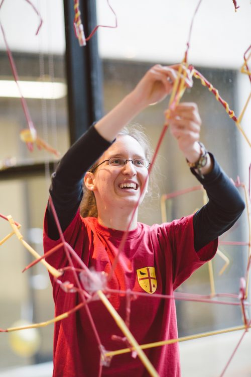 A student adding to the collaborative art straws installation in the Studio