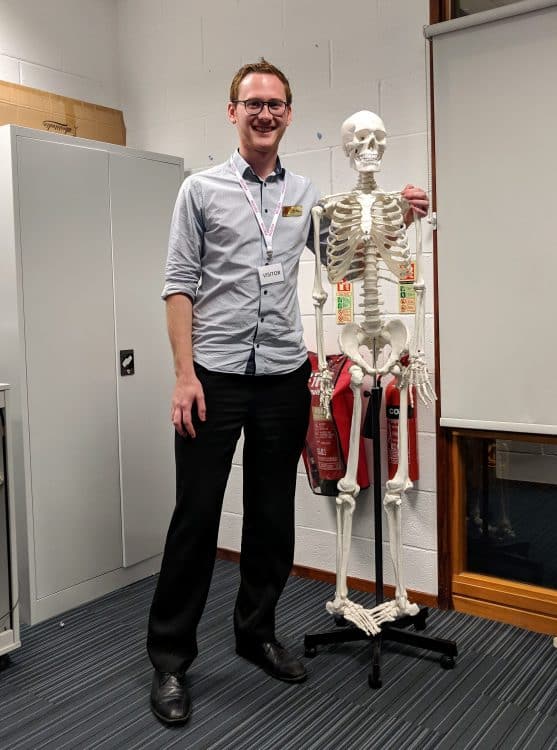 Schools Liaison Officer Luke Maw with a model skeleton who observed his talk at WQE college in Leicester