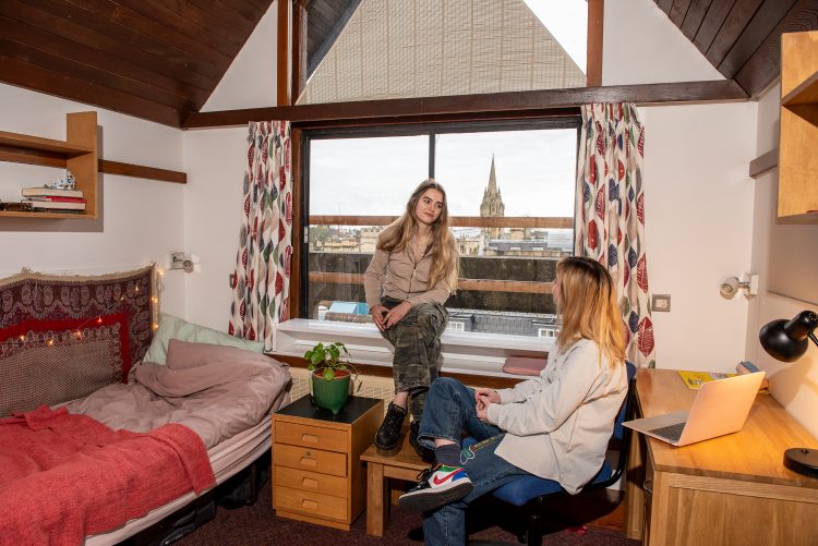 Two students talking to each other in a bedroom in the Kelly Buidling