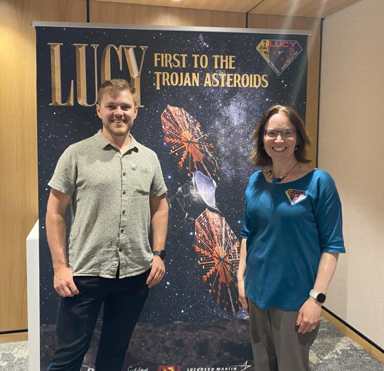Lucy Mission Two people standing next to a banner which reads: Lucy, first to the Trojan asteroids