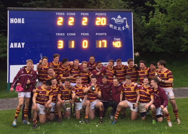 The rugby team celebrating their victory in front of the scoreboard