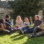 Postgraduate students sitting in the churchyard next to the College Library