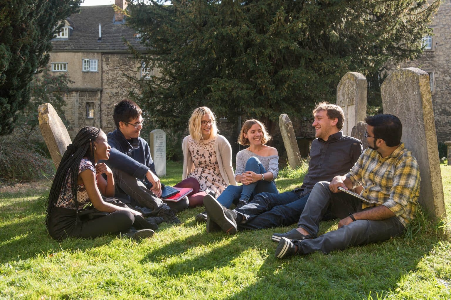 Postgraduate students sitting in the churchyard next to the College Library