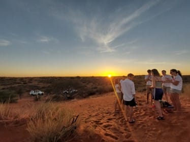 The team watch the sunset over the dunes.
