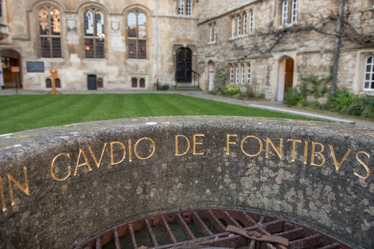 The well, showing part of its inscription, in the College's Front Quad, with the Old Dining Hall in the background