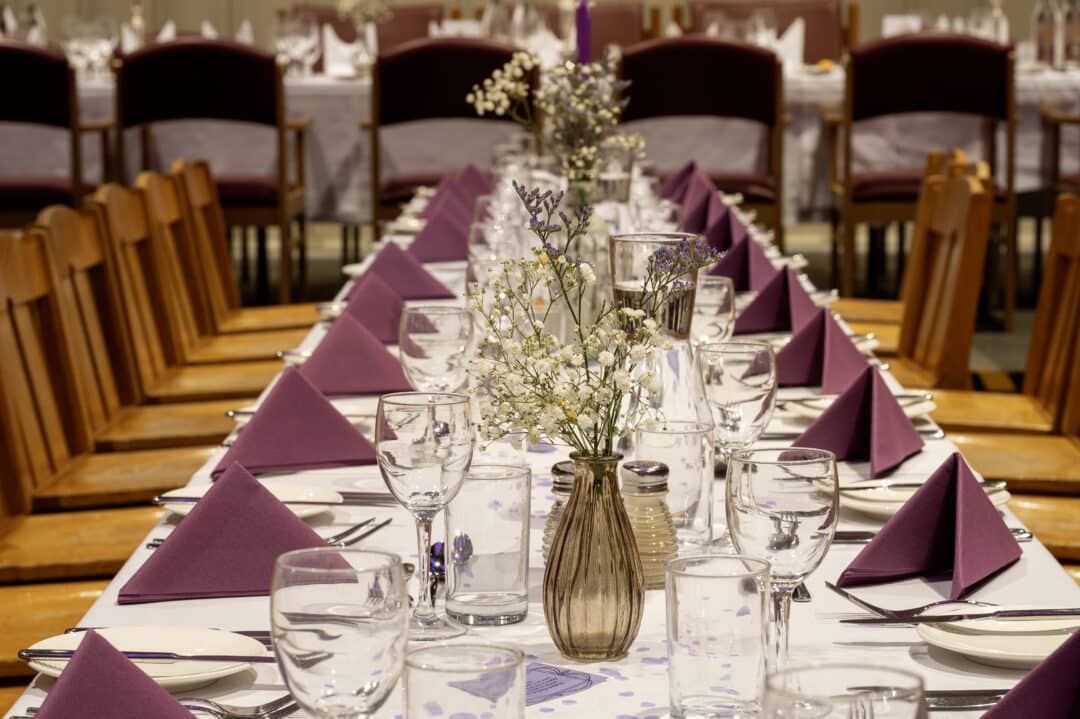 A table set with purple napkins and flowers